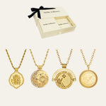 Four gold-toned pendant necklaces displayed below an open cream-colored Meltie & Bloom gift box with a black ribbon, on a light beige background.