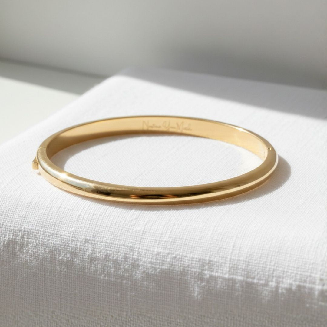 Gold bangle on a white fabric surface