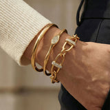 Gold bracelet stack on a wrist with a blurred background