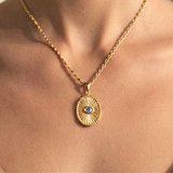 Oval shaped gold with a vibrant blue center stone. A modern talisman designed to protect your peace and elevate your everyday. Featuring radiant sunburst detailing and a striking blue centre stone, this piece is your subtle statement. bold in meaning, timeless in style.
