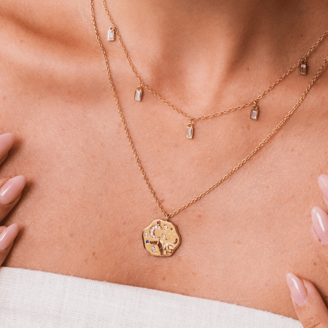 Gold to the moon and back necklace layered with the white chakra necklace on a person's neck. 