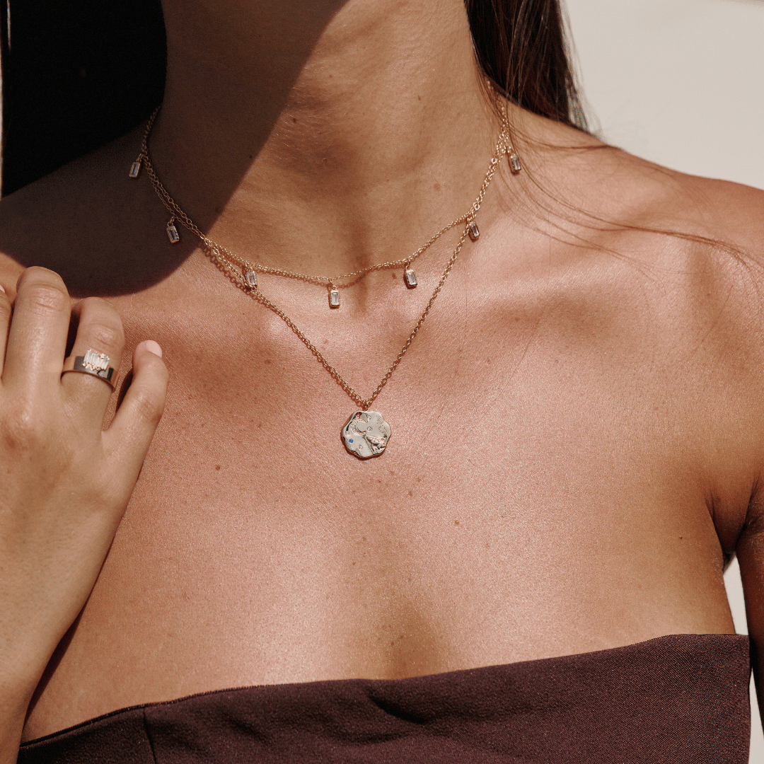 Gold to the moon and back necklace layered with the white chakra necklace on a person's neck. these two necklaces are perfect for layering or wearing solo.