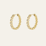 A pair of gold hoop earrings with a textured, bezel design and beaded outer edge. The hoops have small clear stones set along the front, shown on a light cream background.