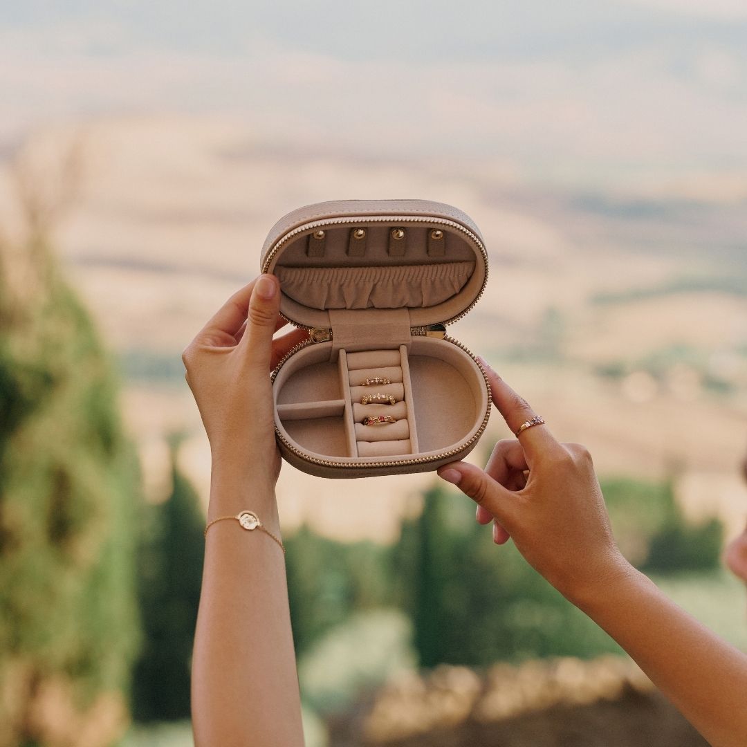Person holding an open luxurious jewellery storage case with a scenic background