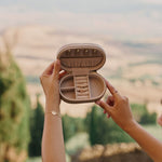 Person holding an open luxurious jewellery storage case with a scenic background
