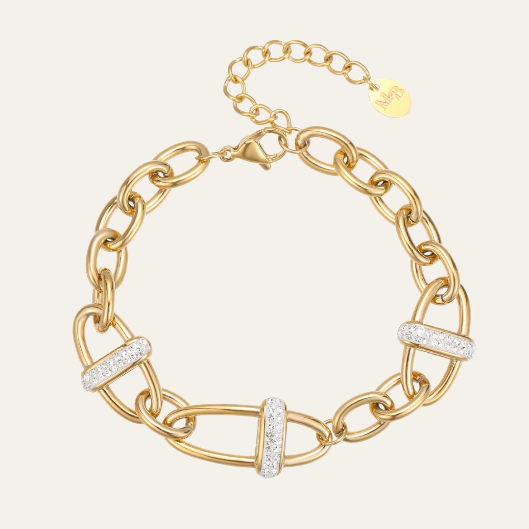 Gold chain bracelet with diamond accents on a light beige background