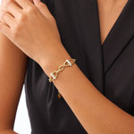 Gold chain bracelet on a person's wrist with a black background