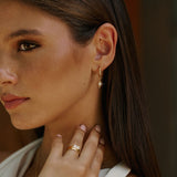 woman wearing the star drop earrings from mettle and bloom. they were designed in house by mettle and bloom. they are a hoop earring with a star suspended from it. 