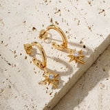 star drop earrings on a tile surface. They were designed in house by mettle and bloom. they are a hoop earring with a star suspended from it. 