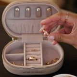 Hand holding a gold ring in front of an open jewelry box with rings inside. The woman is taking jewellery out of jewellery storage case