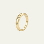 A polished yellow gold band ring with three small, evenly spaced clear gemstones, shown on a light cream background. The stones are small stars and the ring is from Mettle & Bloom's Written in the stars collection. 