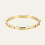 A gold bangle bracelet with small diamond accents, featuring the 'Matte & Bloom' brand name engraved inside, set against a light beige background.