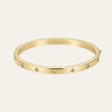 A gold bangle bracelet with small diamond accents, featuring the 'Matte & Bloom' brand name engraved inside, set against a light beige background.